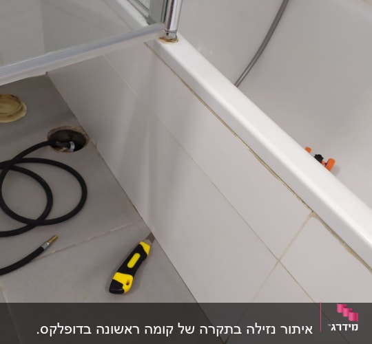 כלי עבודה ליד אמבטיה, צינור וגלאי נזילות